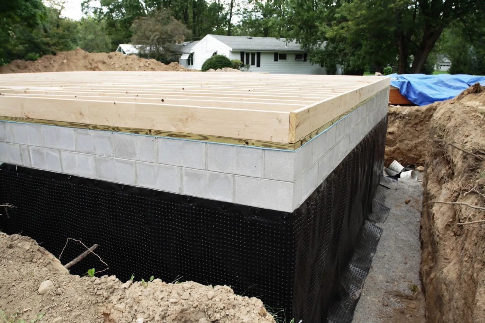 Weeping tile installation cross-section showing perforated pipe and washed stone